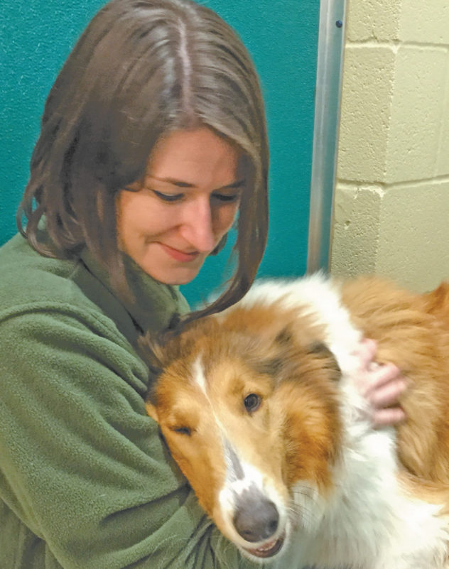 Animal Harbor Manager Amber Kelley snuggles with an adoptable dog.